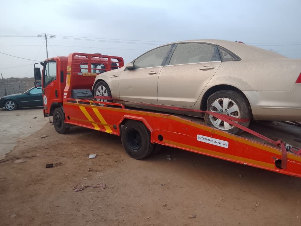 Red tow truck loading a sedan vehicle